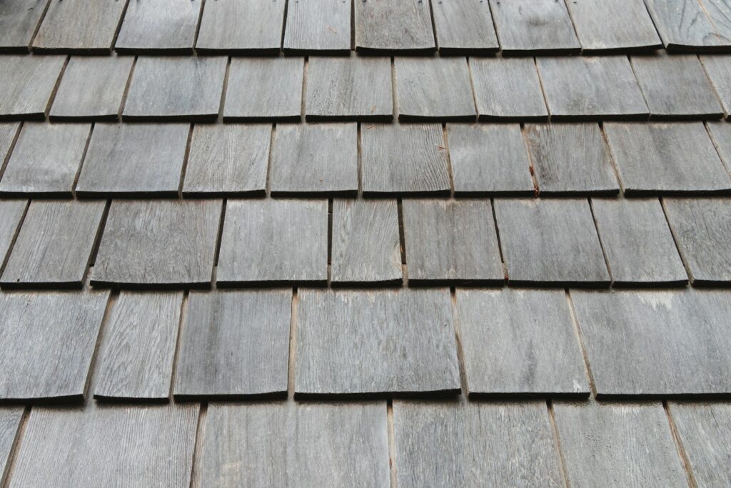 Close-up of overlapping grey wood roof shingles with visible grain